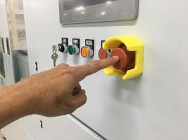 Toque con la mano en la máquina de botón de emergencia en la fábrica industrial foto