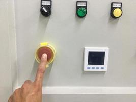 Toque con la mano en la máquina de botón de emergencia en la fábrica industrial foto