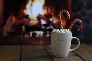 Delicious sweet cocoa with marshmallows and blurred fireplace on background photo