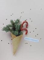 New Year Christmas holiday party celebration waffle cone candy canes fir tree branch copy space color paper background. photo