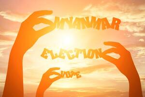 Silhouette of hand holding paper cut text MYANMAR ELECTION VOTE photo