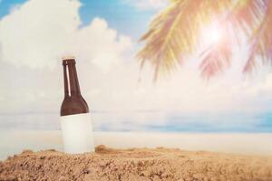 Botella de cerveza con logotipo en blanco en la arena con fondo de playa foto