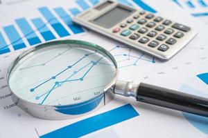 Magnifying glass on charts graphs paper. Financial development, Banking Account, Statistics, Investment Analytic research data economy, Stock exchange trading, Business office company meeting concept. photo