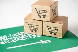 caja con el logotipo del carrito de compras y la bandera de Arabia Saudita, importación, exportación, compras en línea o comercio electrónico, servicio de entrega de finanzas, tienda, envío de productos, comercio, concepto de proveedor. foto