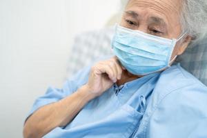 Asian senior or elderly old lady woman patient worry and wearing a face mask new normal in hospital for protect safety infection Covid-19 Coronavirus. photo