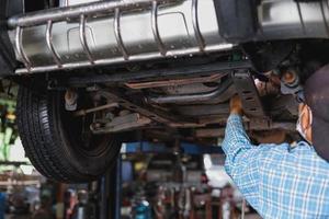 The mechanic is checking the undercarriage of the car. photo