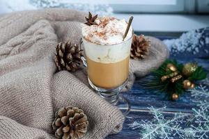 café con leche caliente con ramas de canela, espolvoreado con canela. adornos navideños, ramas de un árbol de navidad. concepto de vacaciones año nuevo.