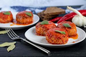 Fish cakes in tomato juice with onions and carrots. Diet. Sauerkraut. On a dark wooden background. photo