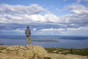 Boy standing on top of a rocky mountain top photo