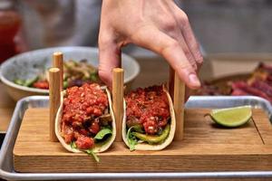 Tacos de cerdo callejeros tradicionales mexicanos con carne de res, tomate, aguacate, chile en tortilla de maíz amarillo foto