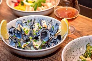 Delicious mussels in restaurant on a wooden table. Tasty seafood with beer in cafe or pub menu. photo