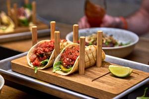 Tacos de cerdo callejeros tradicionales mexicanos con carne de res, tomate, aguacate, chile en tortilla de maíz amarillo foto