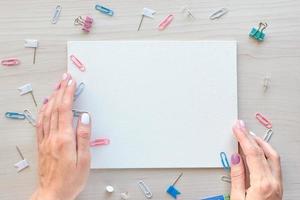 School office supplies on wooden background. Back to school concept. White board with hands for copy space. Top view ready for your design photo