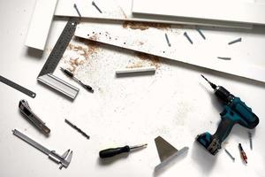 Man doing renovation work at home, drilling with a screwdriver. Group of repair tools on wooden white background. photo