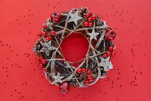 Christmas Wreath Made of branches decorated with gold wooden stars and red berry bubbles isolated on red background. Creative diy craft hobby. Making handmade craft christmas decorations banner photo