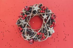 Christmas Wreath Made of branches decorated with gold wooden stars and red berry bubbles isolated on red background. Creative diy craft hobby. Making handmade craft christmas decorations banner photo