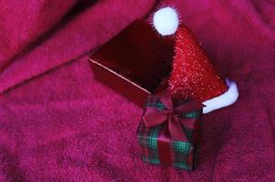 Caja de regalo y gorro de navidad con macro cerrar sobre fondos de alfombra roja foto