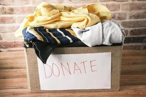 Donation box with donation clothes on a wooden table . photo