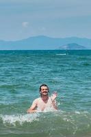 guapo divirtiéndose en el mar, salpicaduras de agua. concepto de vacaciones de verano