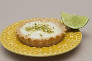 Side view of lemon tart on dish plate with lemon slices on table. photo