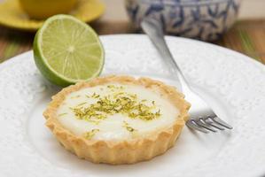 Side view of lemon tart on dish plate with lemon slices on table. photo