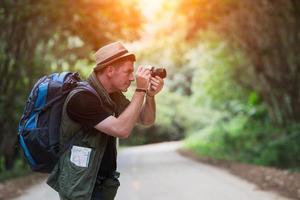 Young man backpacker travelling and photographer in local countryside Thailand photo