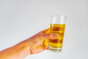 mano con vaso lleno de cerveza sobre fondo blanco. salud. foto