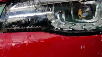 Close-up of water flowing on car headlights during car wash. Car Wash Business Banner.