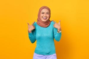 Beautiful cheerful young Asian woman pointing fingers herself on yellow background photo