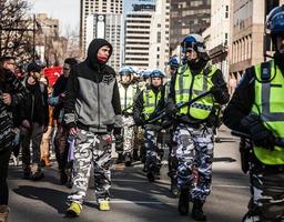 Montreal, Canadá 02 de abril de 2015 - policía y manifestante mirándose a los ojos y vistiendo los mismos pantalones militares