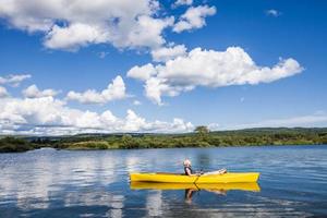 Río tranquilo y mujer relajante en un kayak foto