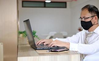 Businessman using his laptop and phone at work photo