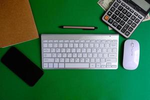 Plano superior de un escritorio de mesa de oficina en plano. un espacio de trabajo con una computadora portátil en blanco, herramientas de oficina, un lápiz, un teclado y una taza de café foto