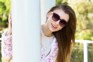 Close up young woman hiding behind a column in a park portrait photo