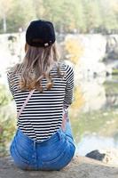 Enjoying the nature. Young woman sitting on stone and enjoying the fresh air and beautiful view green forest. photo