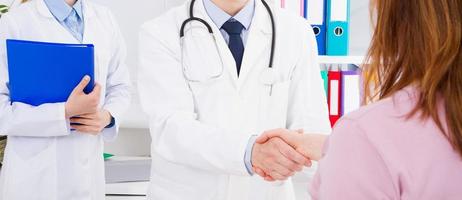 doctor posing in office with medical staff, he is wearing a stethoscope photo