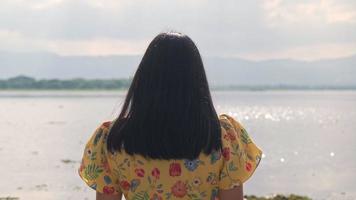 turista mujer asiática disfrutando de la vista con humor feliz junto al lago en un día soleado. viajes al aire libre y tema de la naturaleza. video