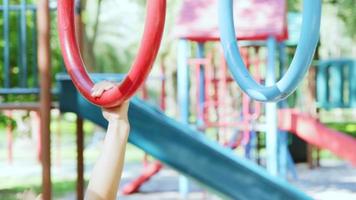 Happy little girls having fun on colorful bar at outdoor playground. Active kid hang on colorful monkey bars in the park. Play is learning in childhood. video