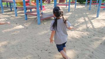 Active little sisters are running in the outdoor playground in the park. Happy child girls smiling and laughing on children playground. The concept of play is learning in childhood.
