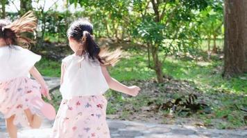 Active little sisters are running in the outdoor playground in the park. Happy child girls smiling and laughing on children playground. The concept of play is learning in childhood. video