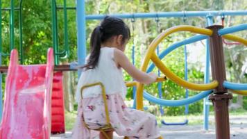 gelukkig klein meisje plezier op carrousel buitenshuis. actief meisje op kinderspeelplaats in het park. het concept van spelen is leren in de kindertijd. video