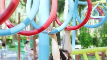 Happy little girls having fun on colorful bar at outdoor playground. Active kid hang on colorful monkey bars in the park. Play is learning in childhood. video