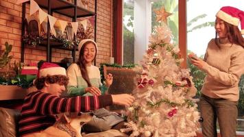 familj med hund och vänner tillsammans dekorerar glatt den vita julgranen i hemmets vardagsrum, roligt och glad förbereder sig för en fest för nyårsfesten. video