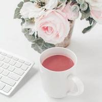 white workspace with light pink note book and white flower with coffee on white table. photo