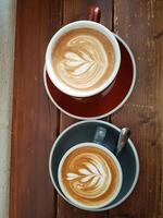 two milk coffees in the shape of a tree in a cup on a wooden table photo