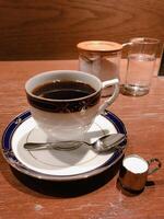 black coffee in a white cup on a wooden table photo