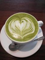 Green tea coffee with heart-shaped milk in a white cup
