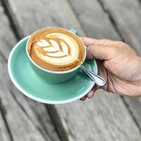 uniquely shaped milk coffee inside a green cup photo