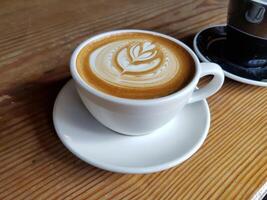 milk coffee with a leaf in the middle in a cup photo