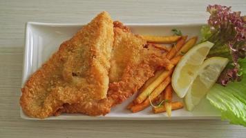 Fish and chips - Filete de pescado frito con patatas fritas y limón en la placa blanca.